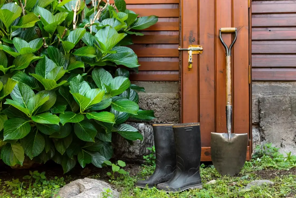 schuafel-und-regenstiefel-an-gartentoilette-angelehnt