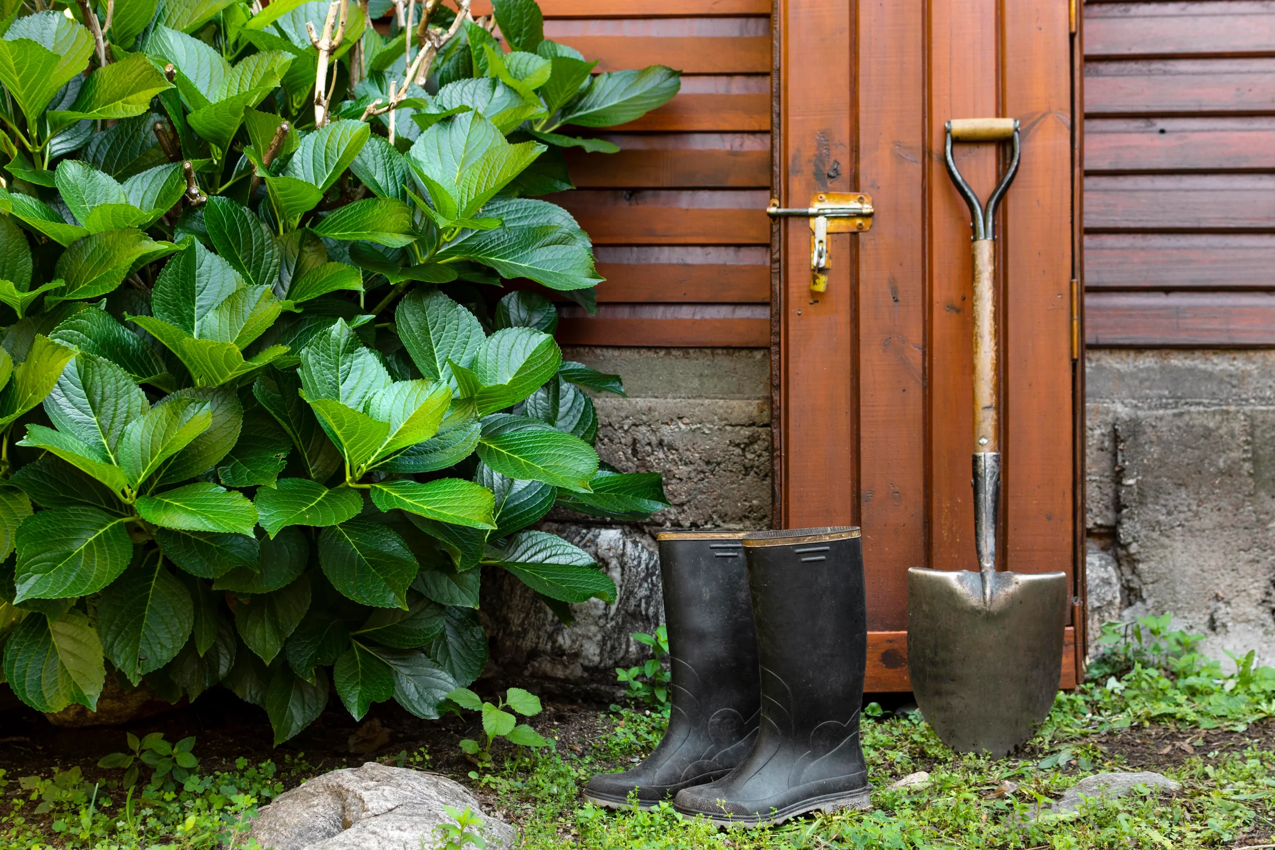 schuafel-und-regenstiefel-an-gartentoilette-angelehnt